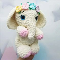 a crocheted stuffed elephant with flowers on it's head is shown in front of a star