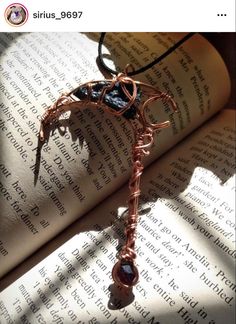 an open book with a wire wrapped necklace on it