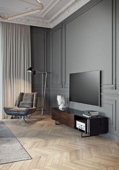 a living room with grey walls and wood flooring, an entertainment center and a black chair