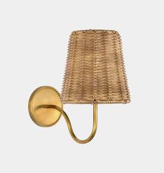 a wall light with a wicker shade on the side and a gold metal arm