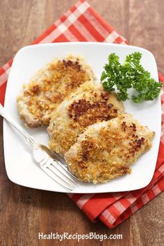 two pieces of chicken on a white plate with a red and white checkered napkin