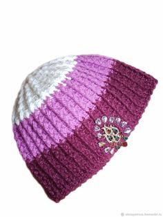 a purple and white knitted beanie with a jeweled brooch on it