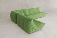 two green couches sitting next to each other on a white surface with no one around them