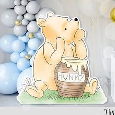 there is a bear that is sitting next to a basket with balloons in the background