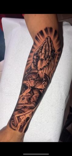 a person with a tattoo on their arm holding a rosary and praying hands in front of them