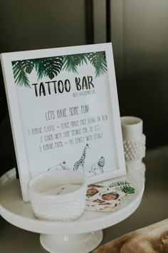 a sign that says tattoo bar on top of a cake plate with other items around it