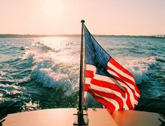 an american flag is waving on the back of a boat