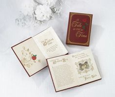 two wedding cards and a box on a white tablecloth with flowers in the background