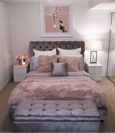 a bedroom with a bed, ottoman and pictures on the wall above it that is decorated in pink and grey tones