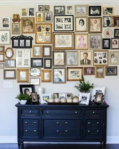 a wall full of framed pictures and photos on it's sideboard in a living room