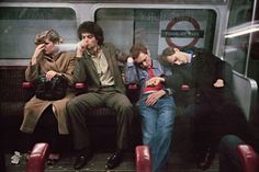 four people sitting on a subway car with their backs to each other