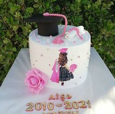 a white cake with pink flowers and a black hat on top that says class of 2010