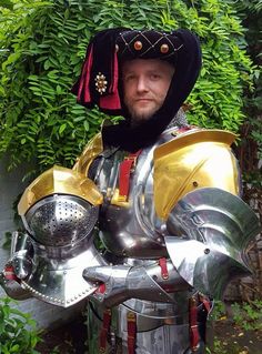 a man dressed as a knight standing next to a bush