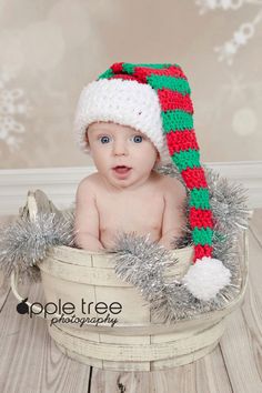 a baby wearing a christmas hat sitting in a bucket