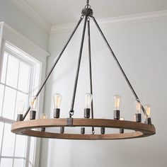 a wooden chandelier with six lights hanging from it's center beam in front of a window