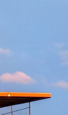 an airplane is flying in the sky above a fenced area with a metal roof