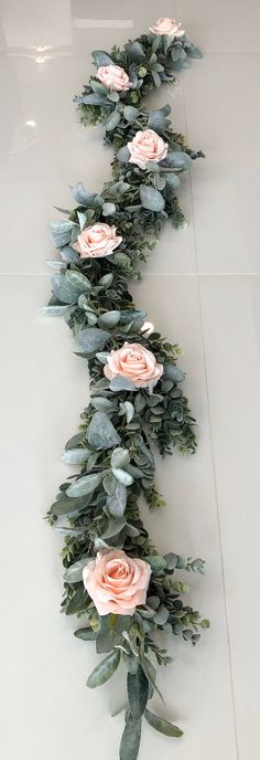 a long line of pink roses and eucalyptus leaves