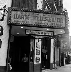 an old theater sign on the side of a building in black and white with people walking by