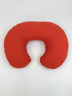 an orange neck pillow sitting on top of a white table next to a red object