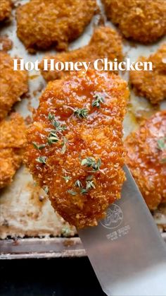 a close up of food on a pan with a knife in it and the words hot honey chicken