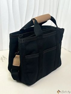 a black bag with a tan handle is sitting on a white counter top and it's zippered to the side