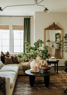 a living room filled with furniture and a large mirror on the wall above it's windows