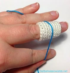 a person's hand with blue and white yarn wrapped around their thumbnails