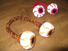 two crocheted eyeballs, one with an orange and white flower on it