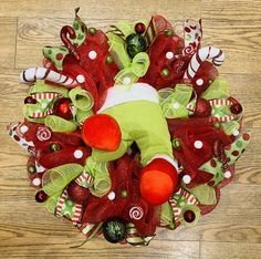 a red and green christmas wreath with a stuffed animal