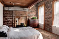 a bedroom with brick walls and white bedding