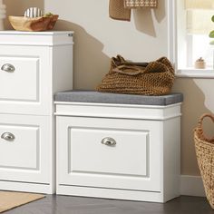 a white bench sitting next to a window in a room with drawers and baskets on the wall