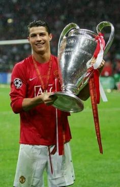 a man holding a trophy on top of a soccer field