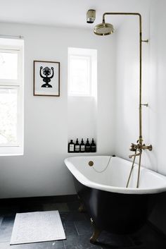 a black and white bathroom with a claw foot bathtub, shower head, and rug