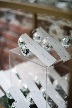 several glass ornaments are on display in a case with white cards attached to the sides