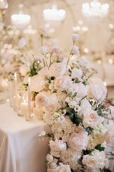 a table with white flowers and candles on it