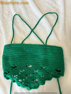 a crocheted green bag sitting on top of a white sheet with holes in it