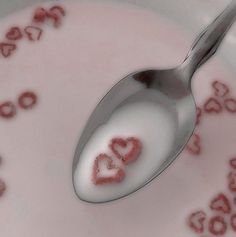 a spoon with the word love on it is in a bowl filled with milk and hearts