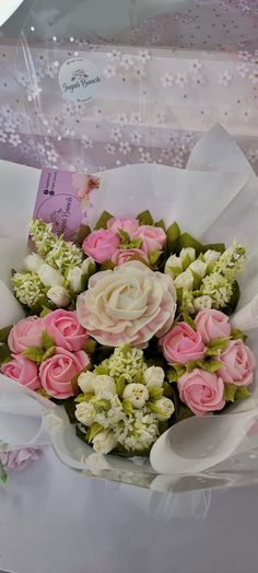 a bouquet of pink and white flowers sitting on top of a table next to a card