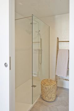 a walk in shower sitting inside of a bathroom next to a basket on the floor