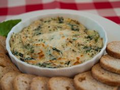 spinach dip in a white bowl surrounded by crackers