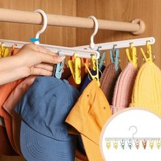 a person is hanging clothes on a rack with hats and umbrellas in front of them