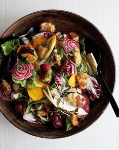 a wooden bowl filled with lots of different types of food on top of a table