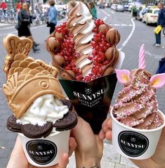 three ice cream sundaes with toppings in their hands on the street corner