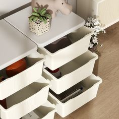 a white table with drawers on it and a plant in the corner next to it