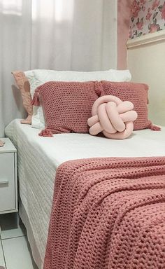 a bed with pink crocheted bedspread and pillows on top of it