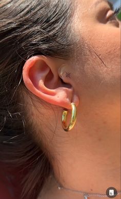 a close up of a person's ear with an earring in the shape of a hoop