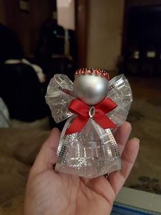 a hand holding a glass angel ornament with a red bow