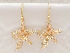 "These are pair of sophisticated and lovely orchid earrings. The beautiful shinning golden plated flower are enhanced with brushed stroke petals. They hang underneath golden plated French ear wires. The earrings measure approximately (32mm) 1.3 inches from the top of the ear wires to the bottom of the flowers. They are perfect for many occasion and everyday wear. They are also a great idea for gift giving and as a little treat for yourself. Your earrings will present in a gift box and tied with Cheap Gold Earrings With Birth Flower Detail, Dainty Gold Flower Earrings For Anniversary, Formal Gold Jewelry With Flower Decoration, Gold Dangle Earrings With Flower Decoration, Delicate Gold Flower Earrings For Anniversary, Delicate Gold Flower Earrings, Gold Delicate Flower Earrings, Gold Dangle Flower Earrings For Bridesmaids, Elegant Gold Earrings With Flower Decoration