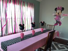 a minnie mouse themed birthday party with pink and black table cloths, polka dot napkins, and mickey mouse decorations