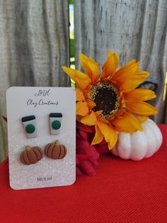 a pair of sunflowers sits next to a card with ear pins on it